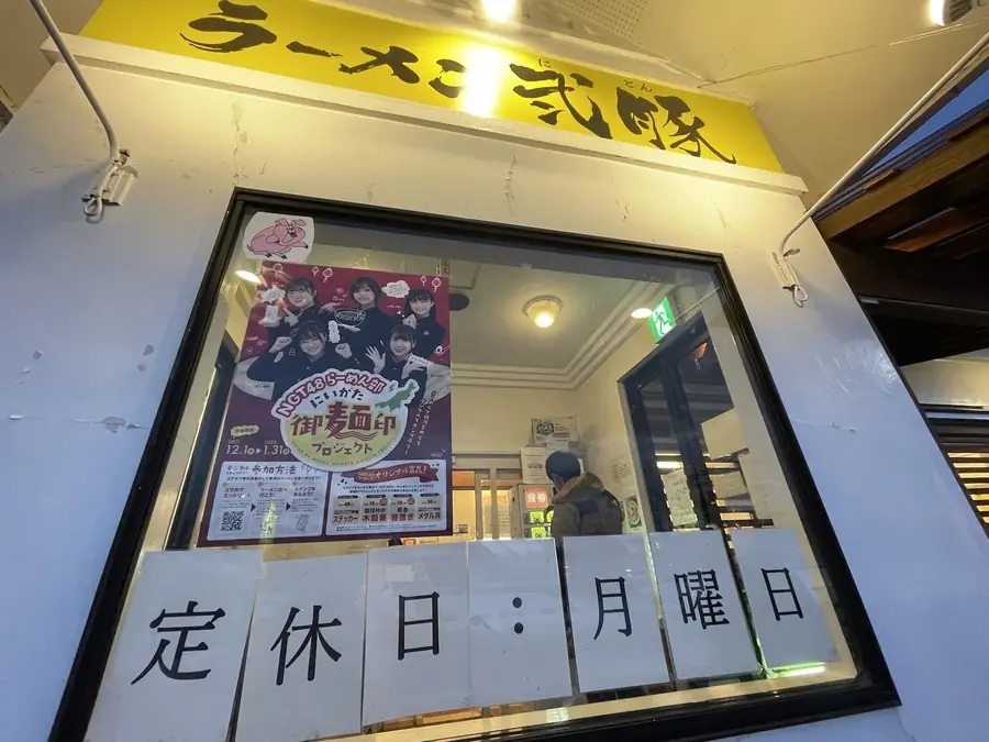 ラーメン弐豚の黄色い看板とにいがた御麺印プロジェクトのポスター